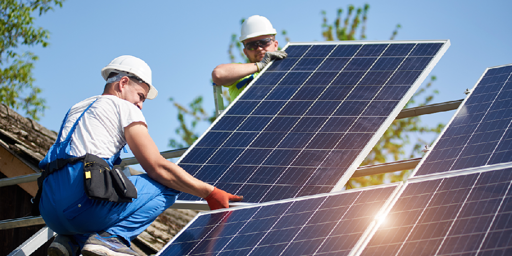Installers fitting solar panels on a roof using an Esdec mounting system.